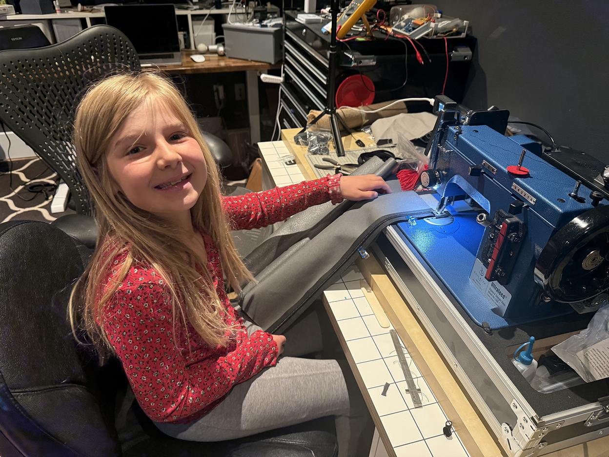 A light grey duffel bag with black straps, made by Zef Houssney