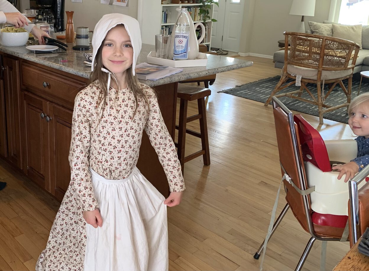 A pioneer-style dress with a beige-background fabric with a rose pattern.