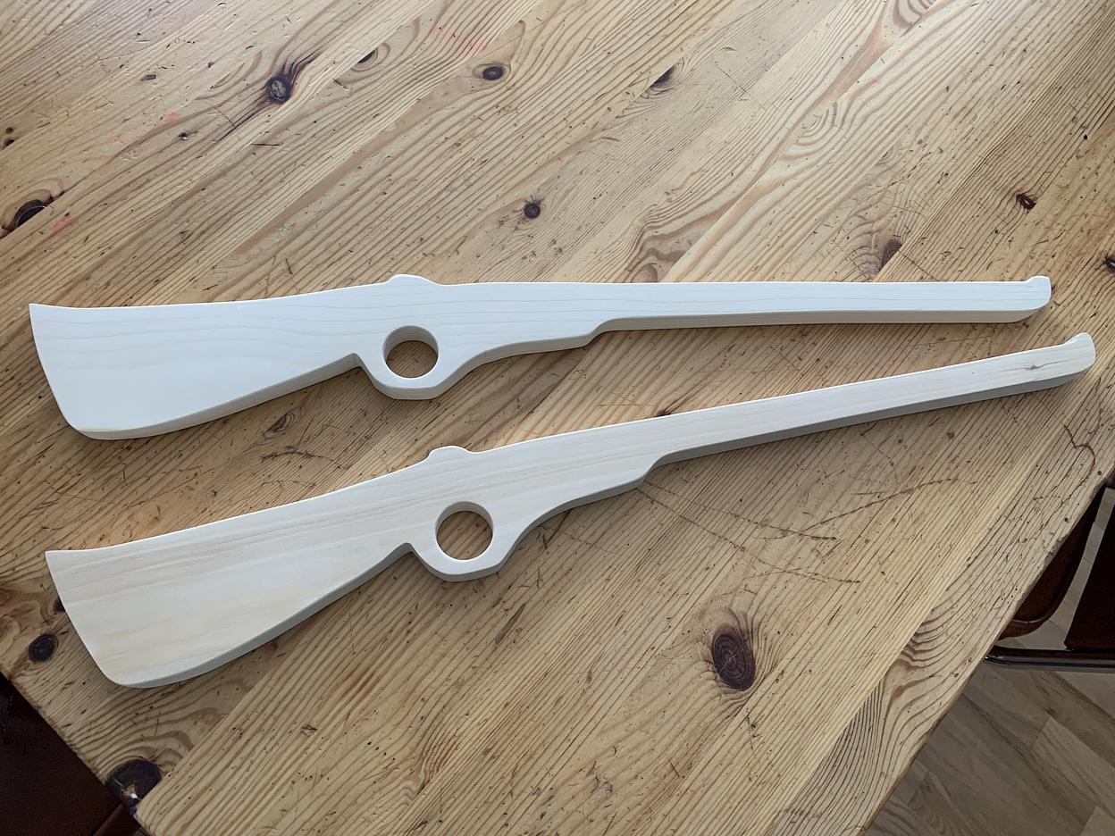 Two wood toy rifle cutouts.