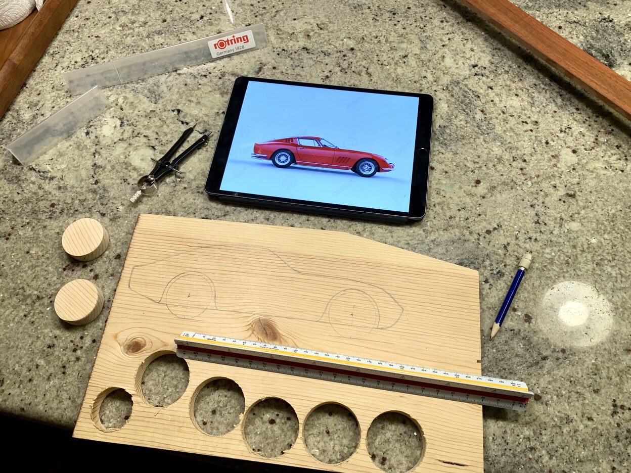 Drawing out the shape of the car on a piece of wood.